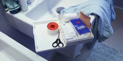 EHBO-kit in de wastafel, met Tempo-tissues, een schaar en andere basisbenodigdheden.